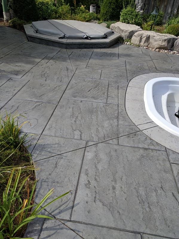 Stamped concrete patio around a hot tub in grey slate