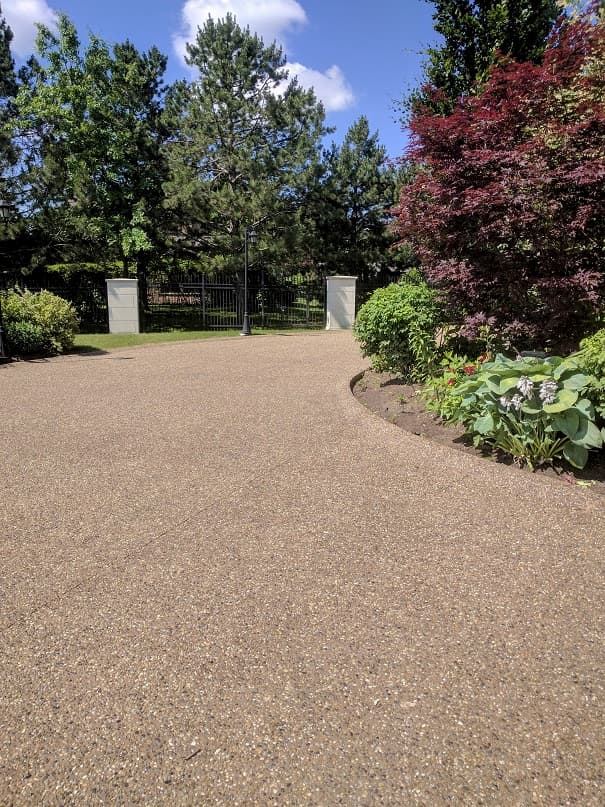 Exposed aggregate driveway curving through a garden